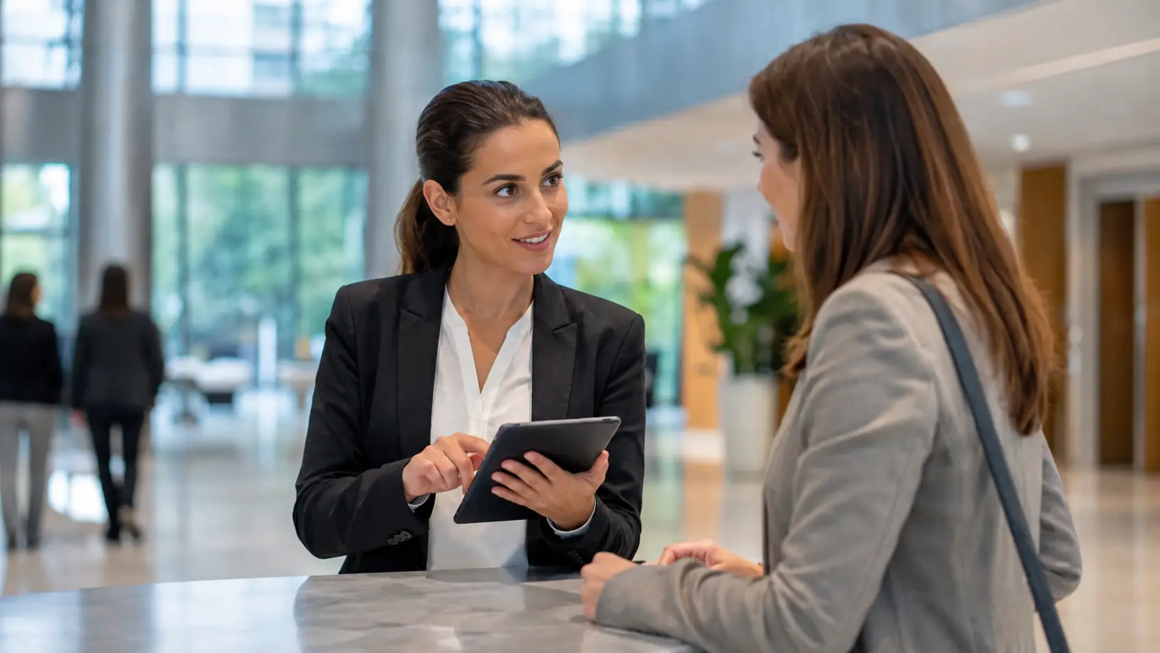 Échange professionnel à l’accueil entre une hôtesse et une visiteuse